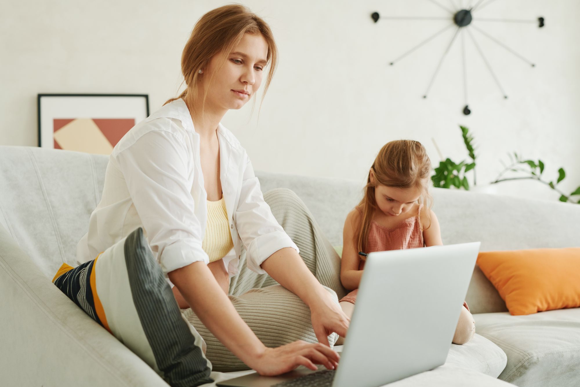 A woman working through the online course on a laptop at home, her daughter sitting beside her.