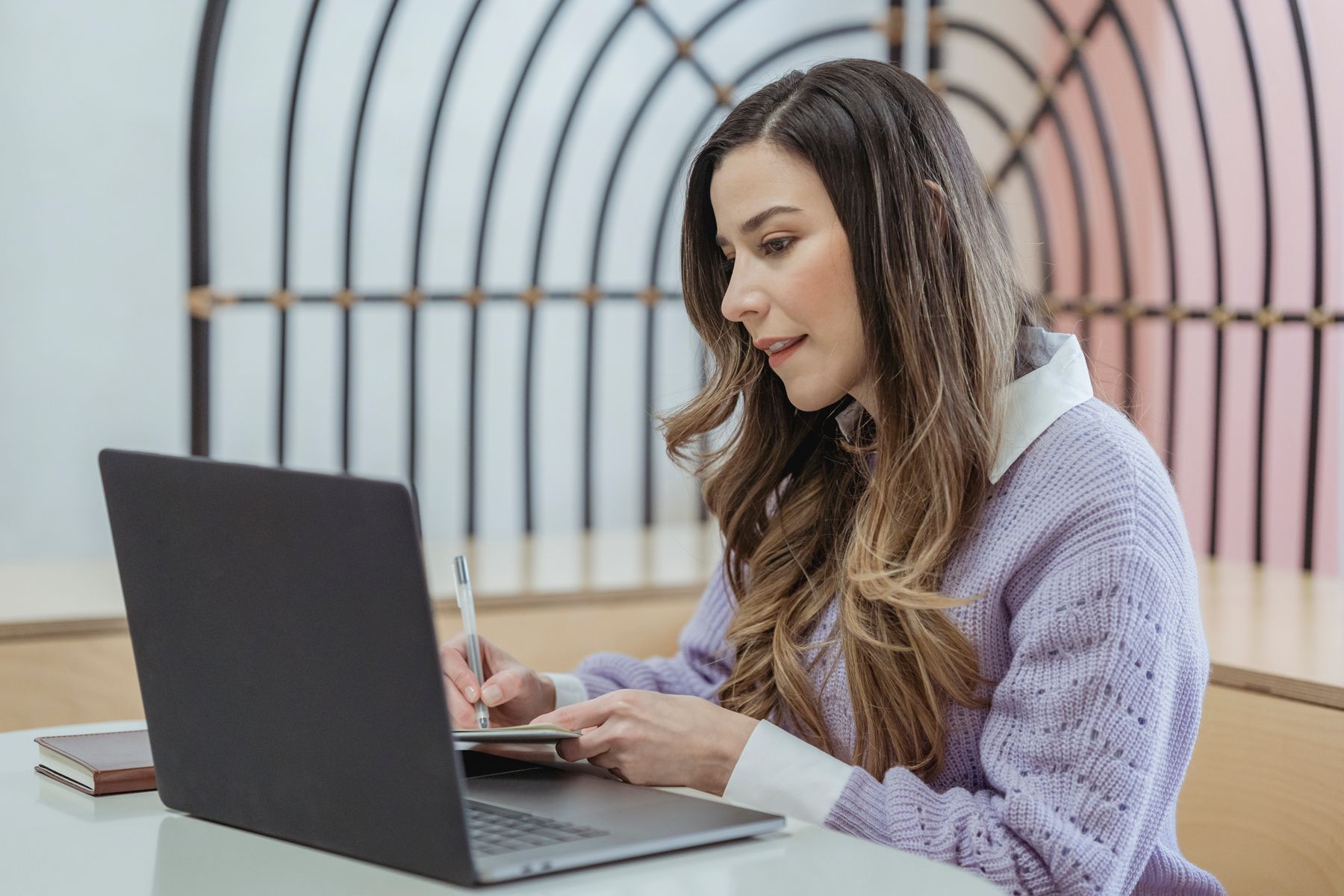 A woman making a note beside her laptop, planning around a deadline.